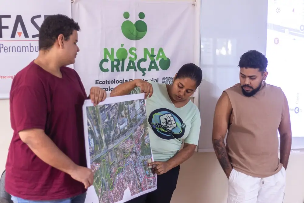 Jovens mostram um mapa de satélite do território com a bandeira do Nós na Criação
