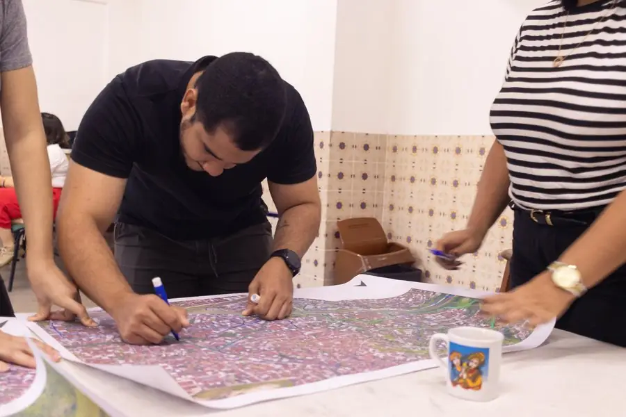 Jovem desenha sobre o mapa do bairro durante oficina de georreferenciamento